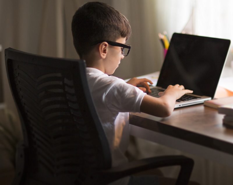 Access-to-the-internet young boy doing homework on laptop